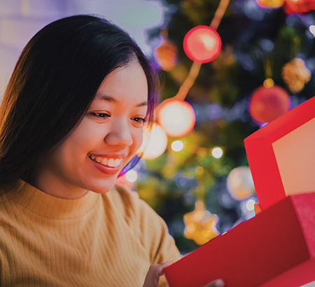 A woman opening a present in front of the tree