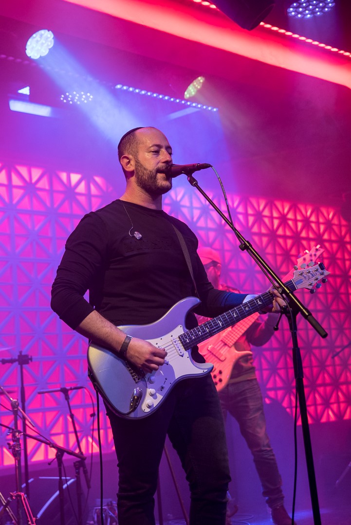 man playing the guitar and singing at a concert